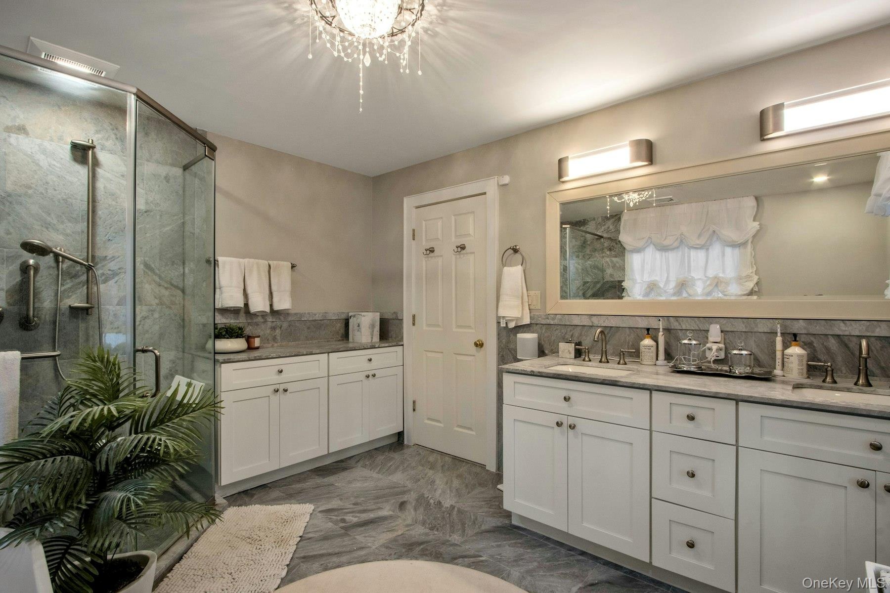 Bathroom featuring decorative backsplash, an enclosed shower, vanity, and an inviting chandelier