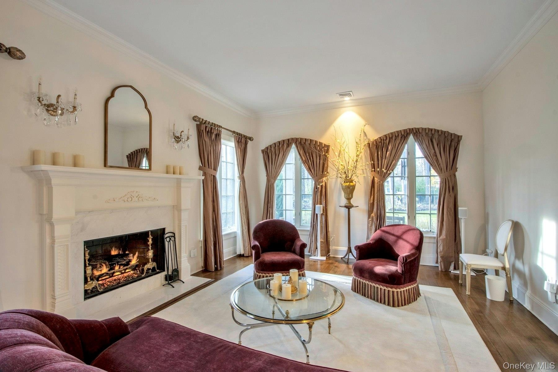 Living room featuring hardwood / wood-style flooring, crown molding, and a high end fireplace
