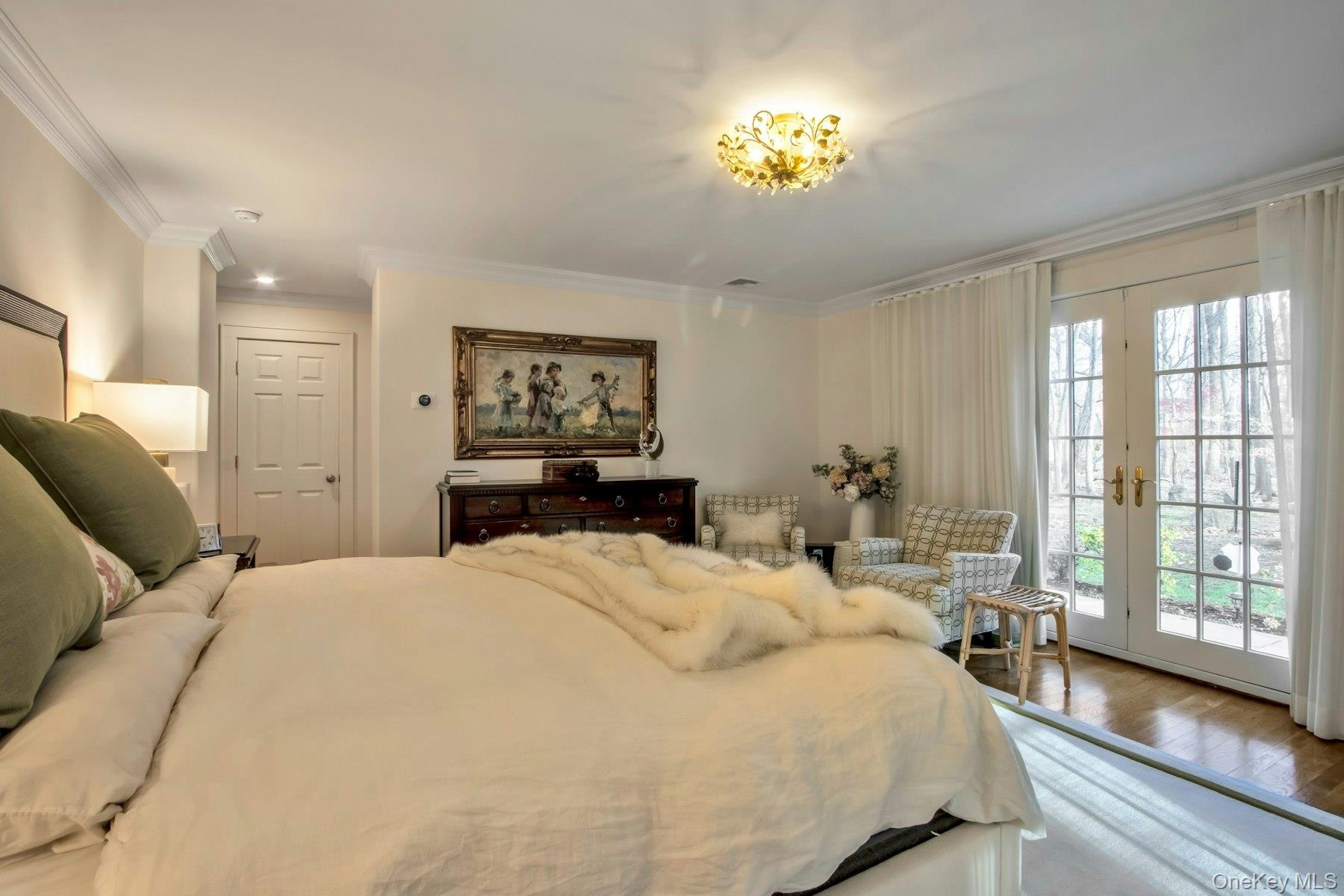Bedroom featuring access to exterior, wood-type flooring, french doors, and ornamental molding