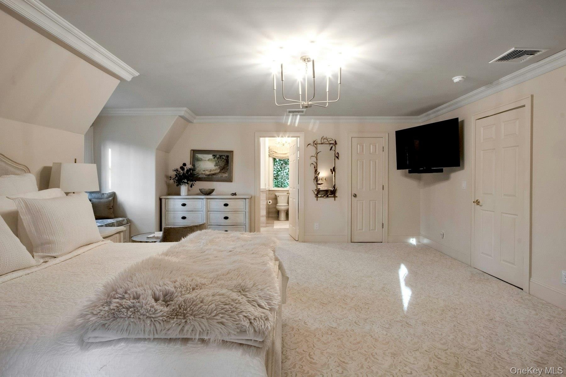Carpeted bedroom featuring ensuite bath and crown molding