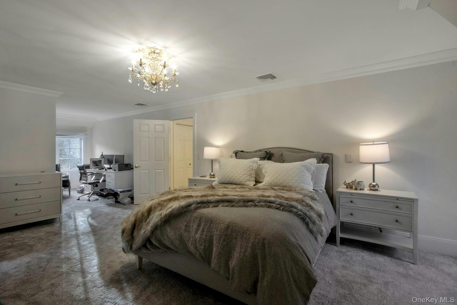 Bedroom with crown molding, a notable chandelier, and dark colored carpet
