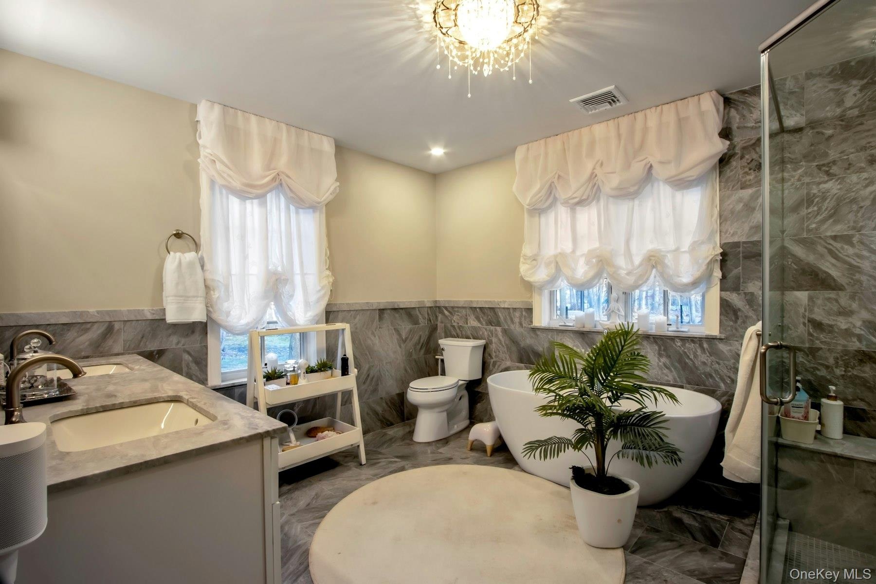 Full bathroom featuring vanity, a healthy amount of sunlight, tile walls, and toilet