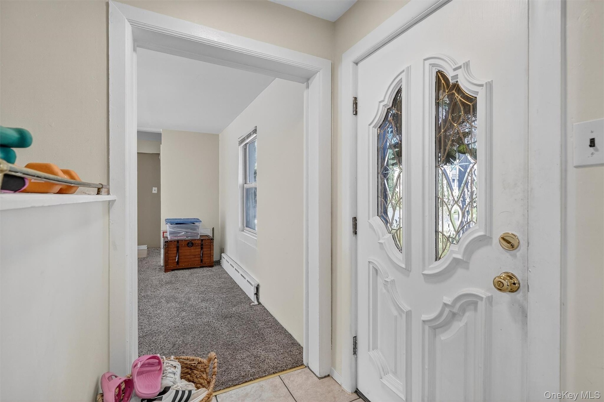 Foyer entrance featuring light carpet, plenty of natural light, a baseboard heating unit, and light tile patterned floors