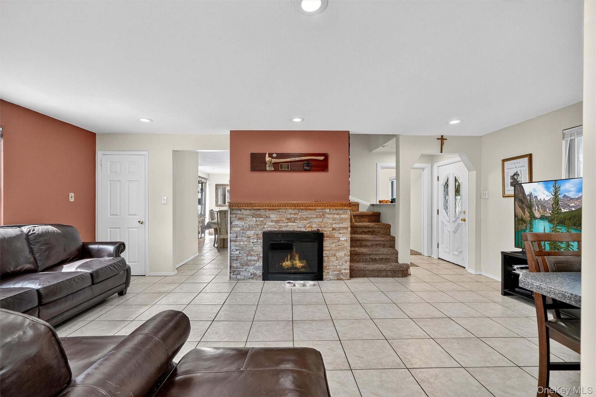 Living room with light tile patterned flooring, recessed lighting, a fireplace, and arched walkways