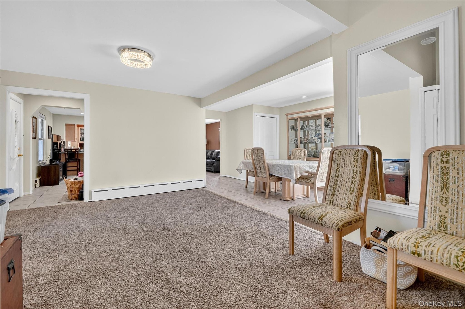 Living area featuring light tile patterned floors, light carpet, and a baseboard heating unit