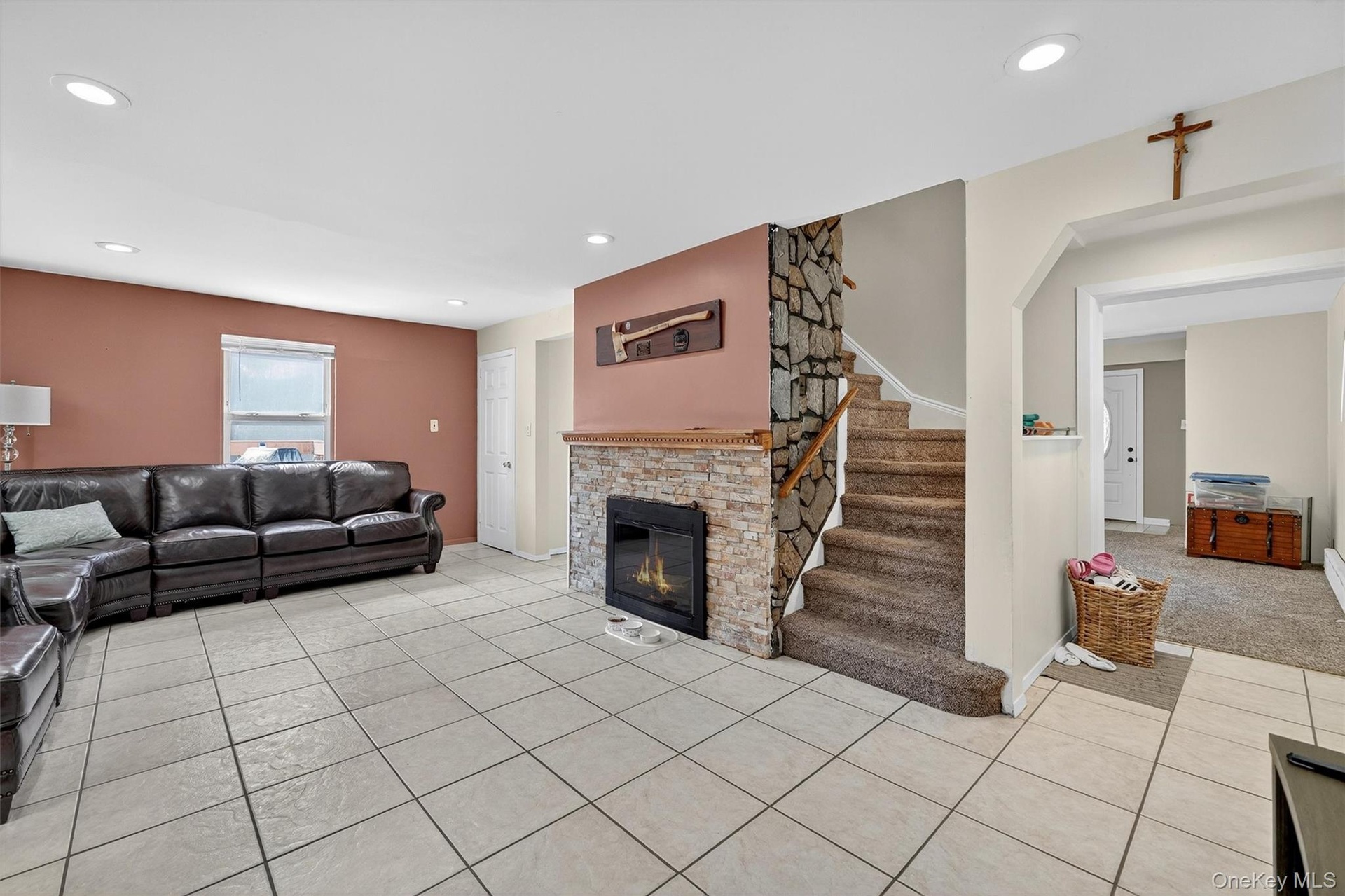 Living room featuring light tile patterned floors, a stone fireplace, recessed lighting, and stairway