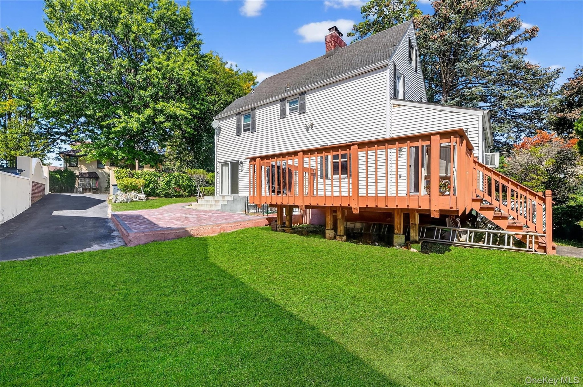 Back of house with a lawn, a chimney, a shingled roof, and a wooden deck