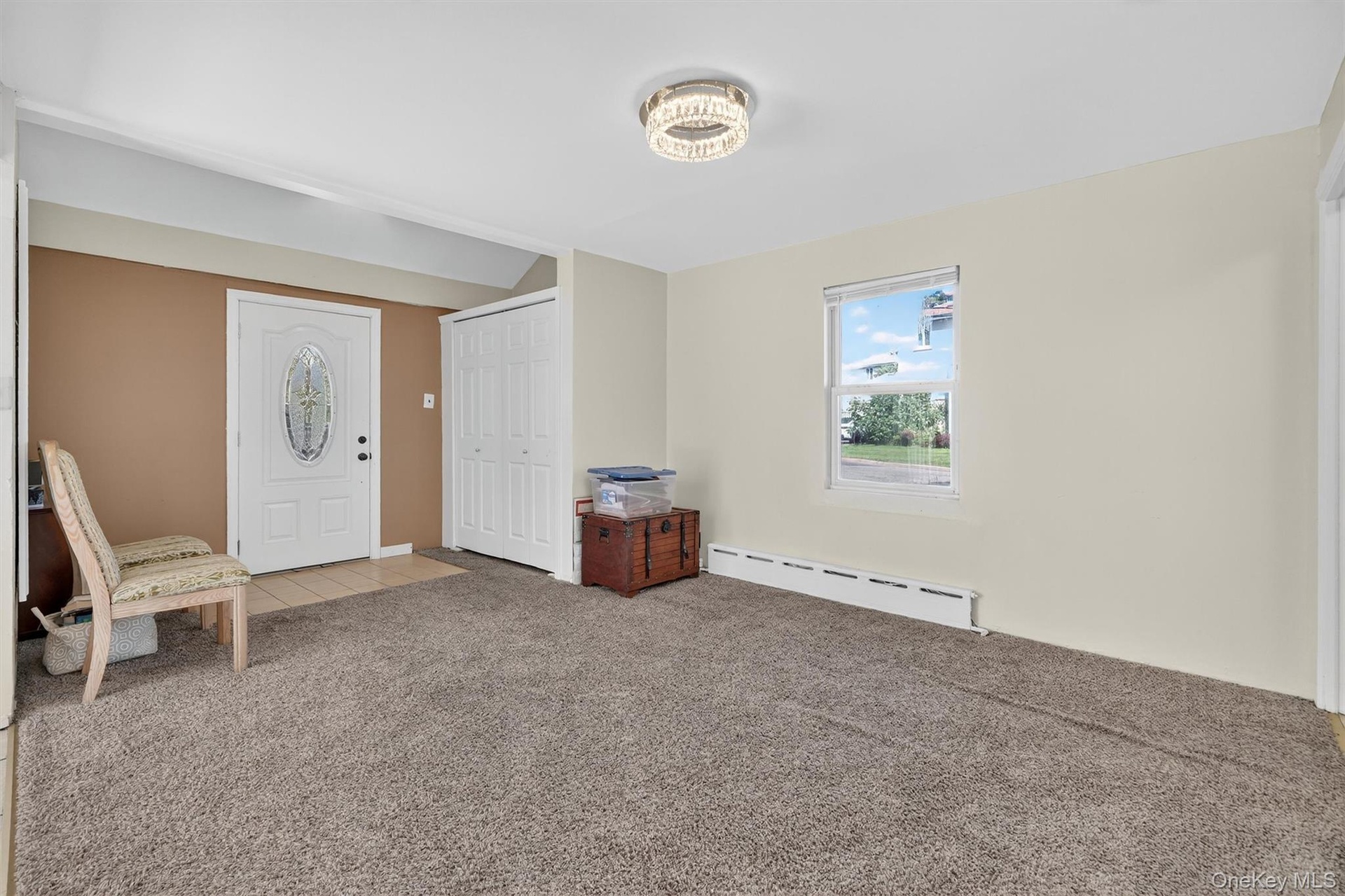 Living area with a baseboard heating unit and carpet flooring