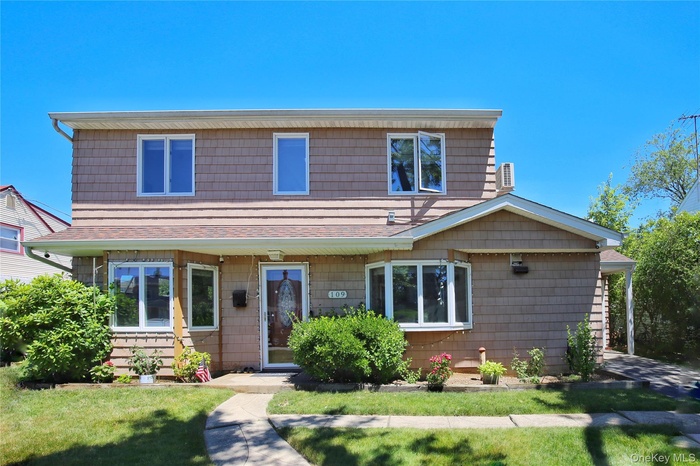 Two-story residence featuring tan shingle siding and a prominent bay window