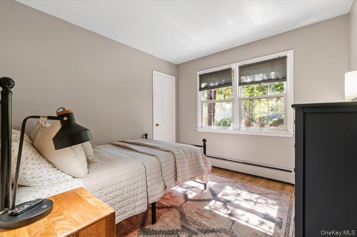 Bedroom featuring wood-finish flooring, neutral wall tones, and a double window with roller shades