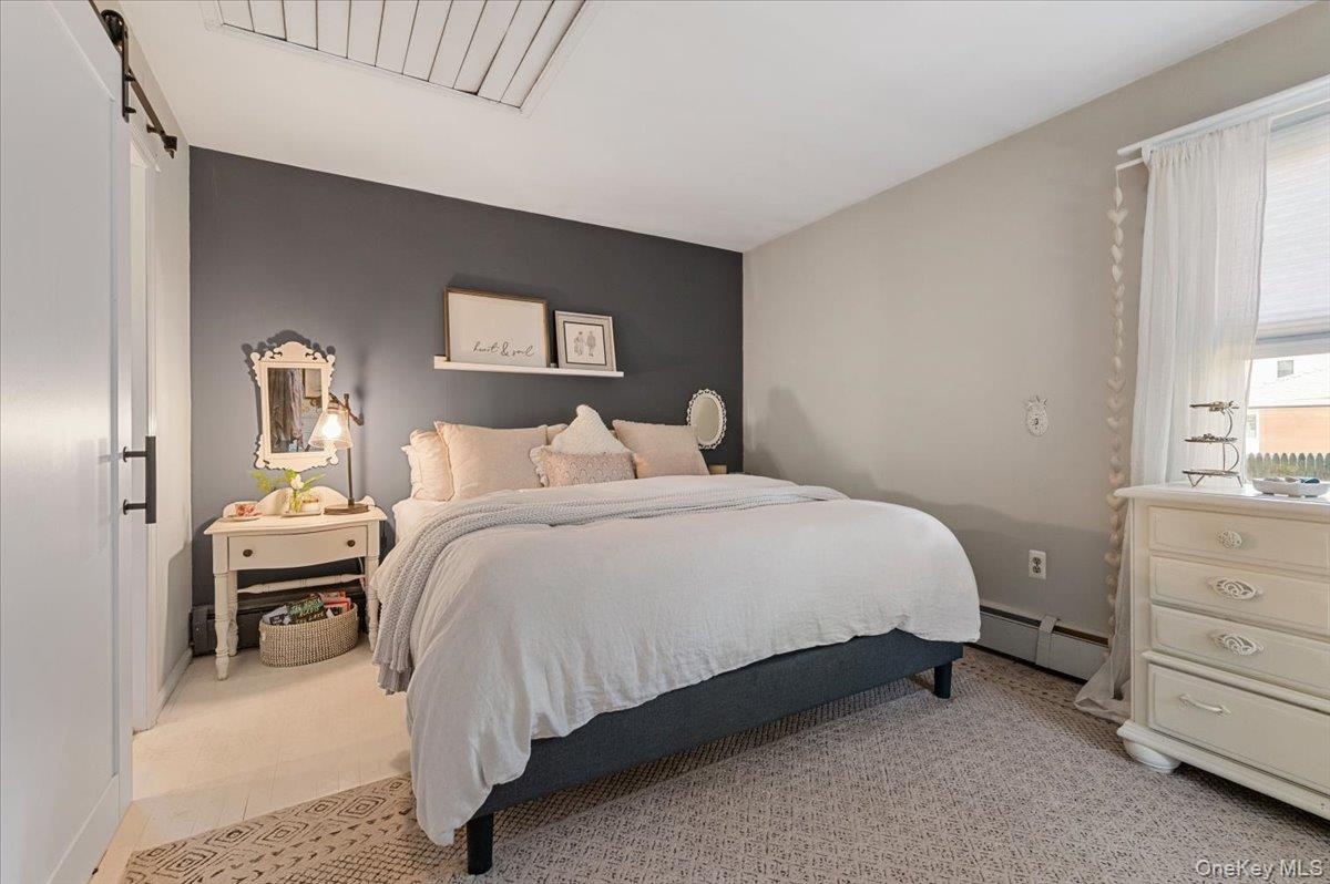 Bedroom featuring a dark accent wall, light neutral wall color, and a window with white blinds