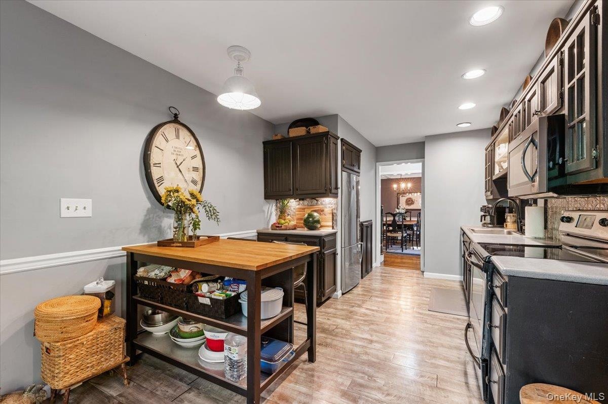 Galley kitchen with dark wood-finish cabinetry, stainless steel appliances, and wood-finish flooring