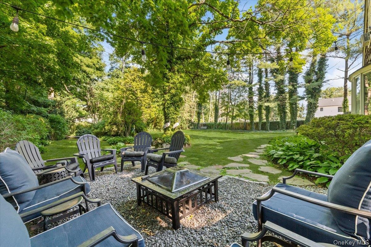 Spacious backyard featuring a stone paver path, mature trees, and string lighting