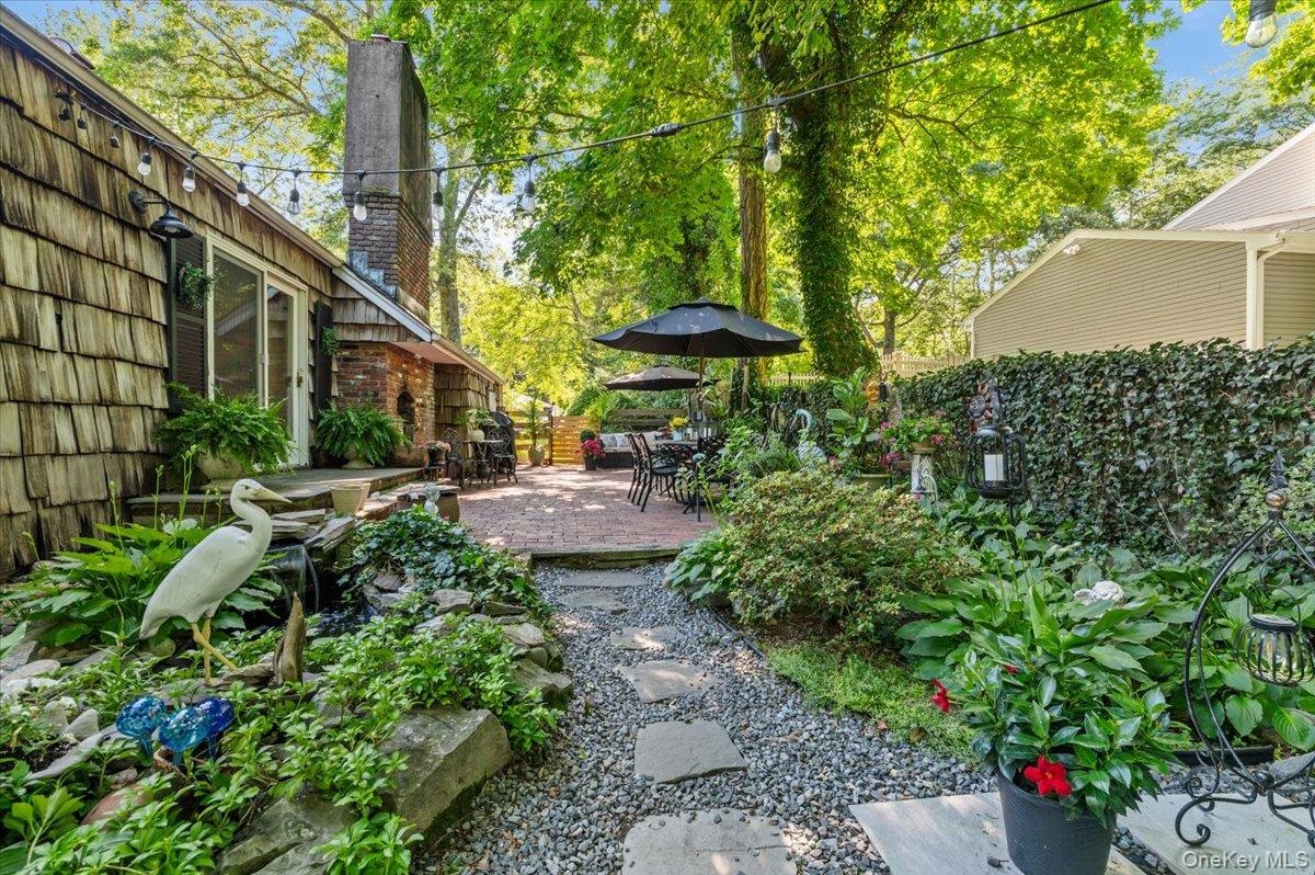 Spacious outdoor patio area featuring a brick paver surface, mature trees, and string lighting