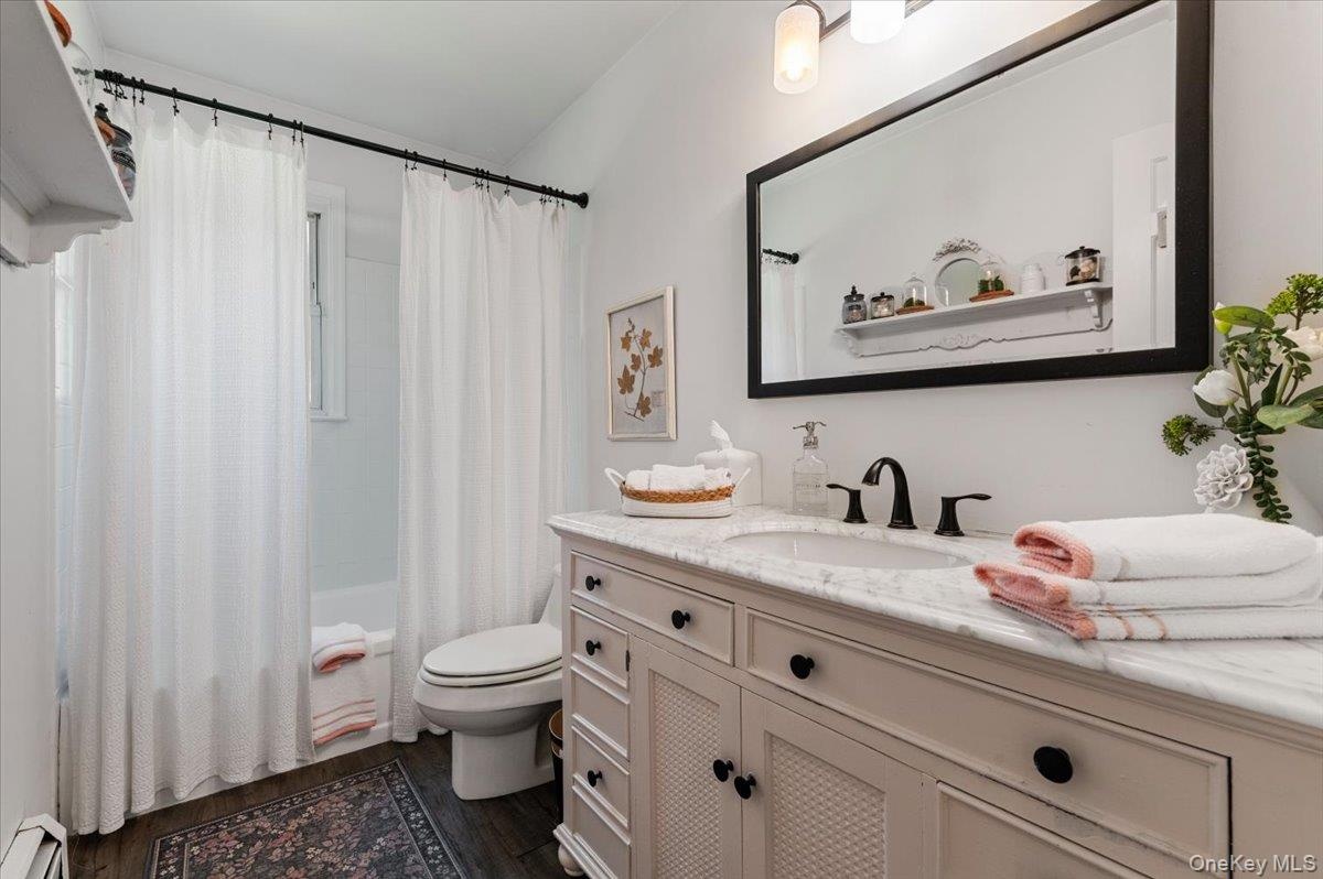 Bathroom featuring a single vanity with a stone countertop, an undermount sink, and a black framed mirror