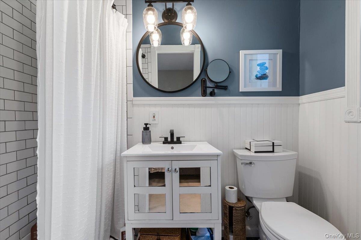 Bathroom featuring a white vanity with integrated sink, black faucet, and mirrored cabinet doors