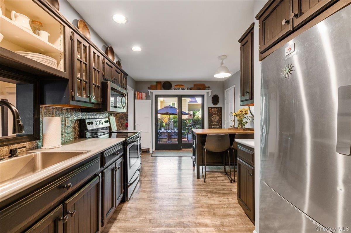 Kitchen featuring wood-finish flooring, dark cabinetry, recessed lighting, and stainless steel appliances