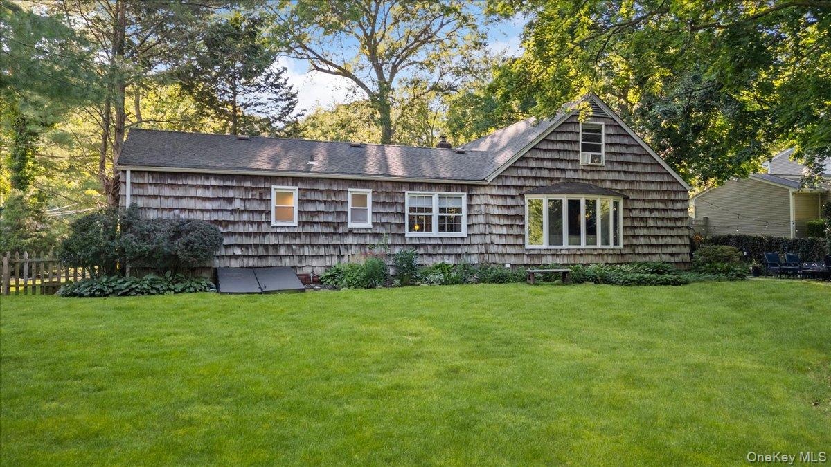 Expansive green lawn, wood shake siding, multiple windows, and a prominent bay window