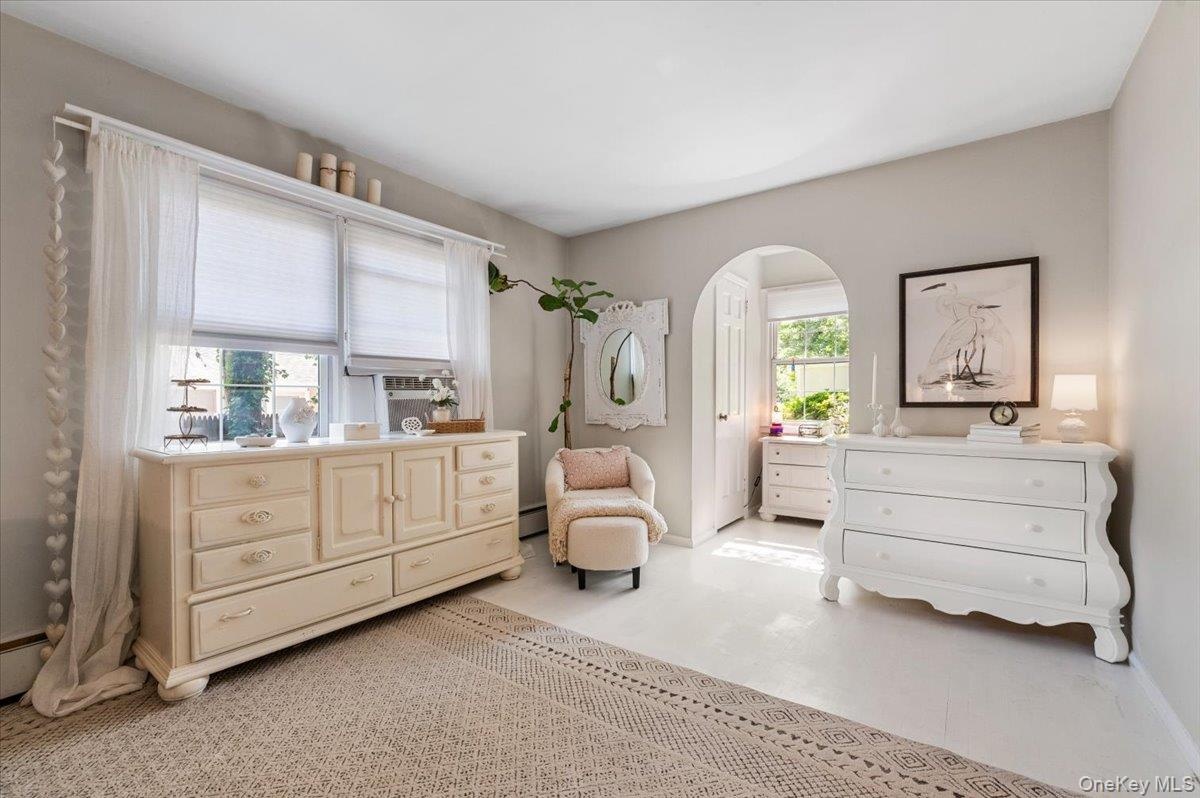 Light-colored walls, white flooring, and a window with blinds and sheer curtains