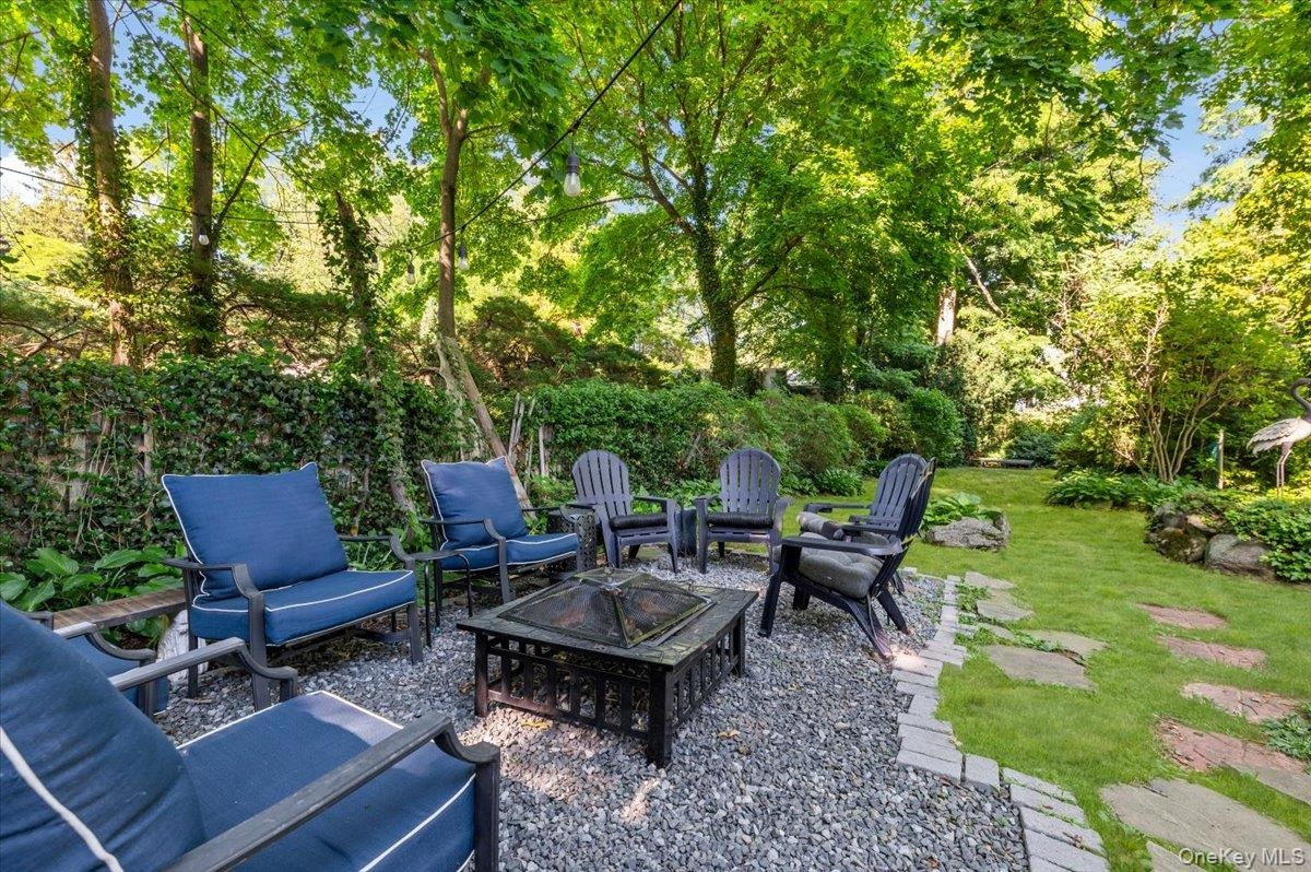 Expansive backyard featuring a stone patio, a manicured lawn, flagstone pathways, and mature trees