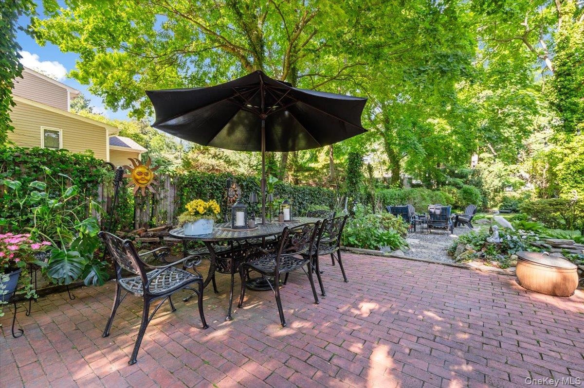 Expansive brick paver patio featuring a dining area under a large umbrella
