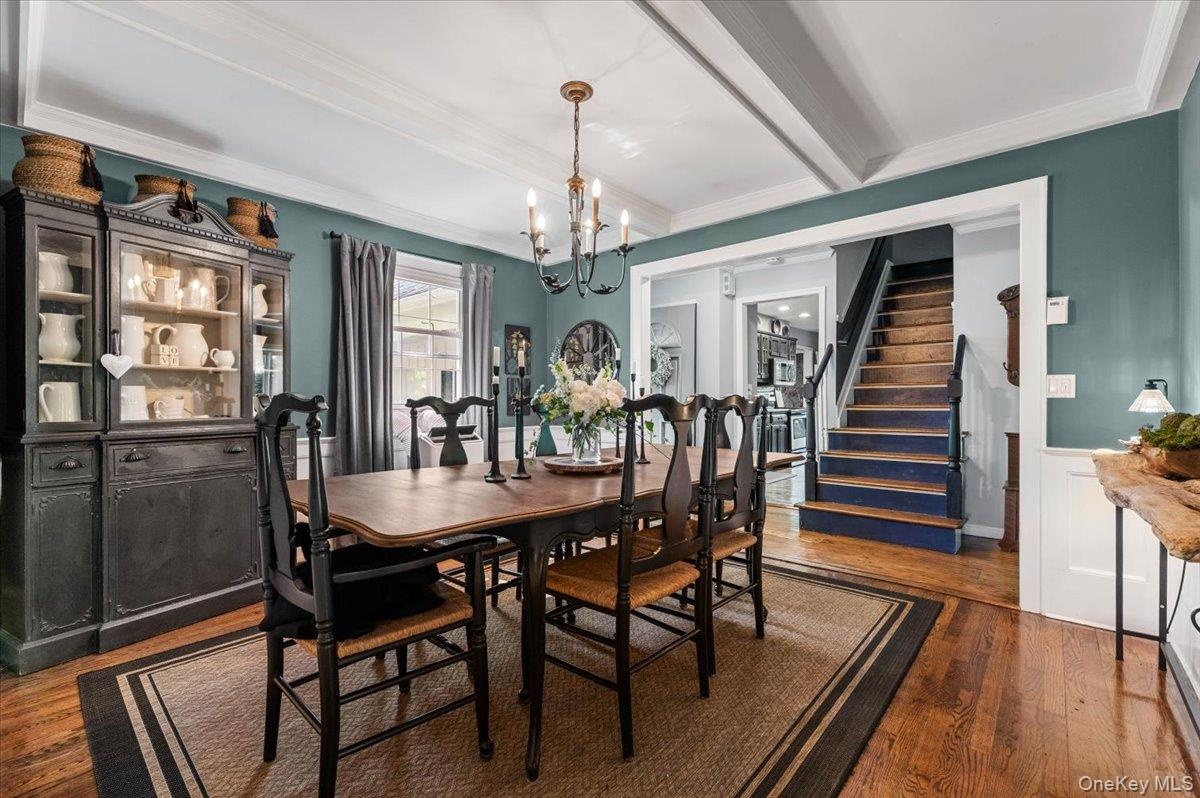 Dining area featuring wood-finish flooring, a coffered ceiling, and a chandelier