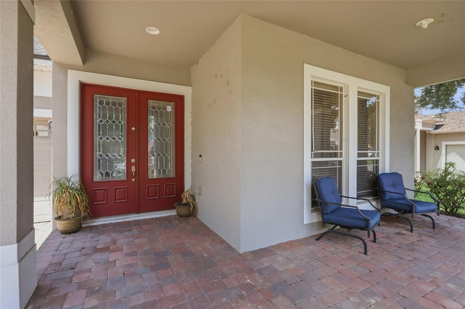 Large covered tiled front porch with double door entrance to the home
