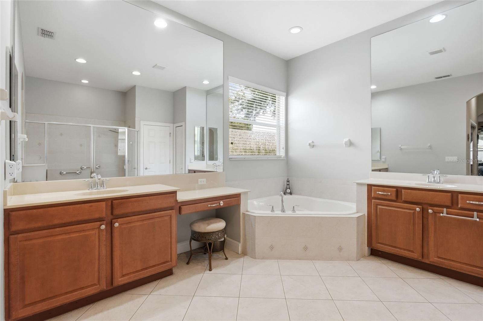 Primary bathroom features dual vanities with dressing area and a garden tub