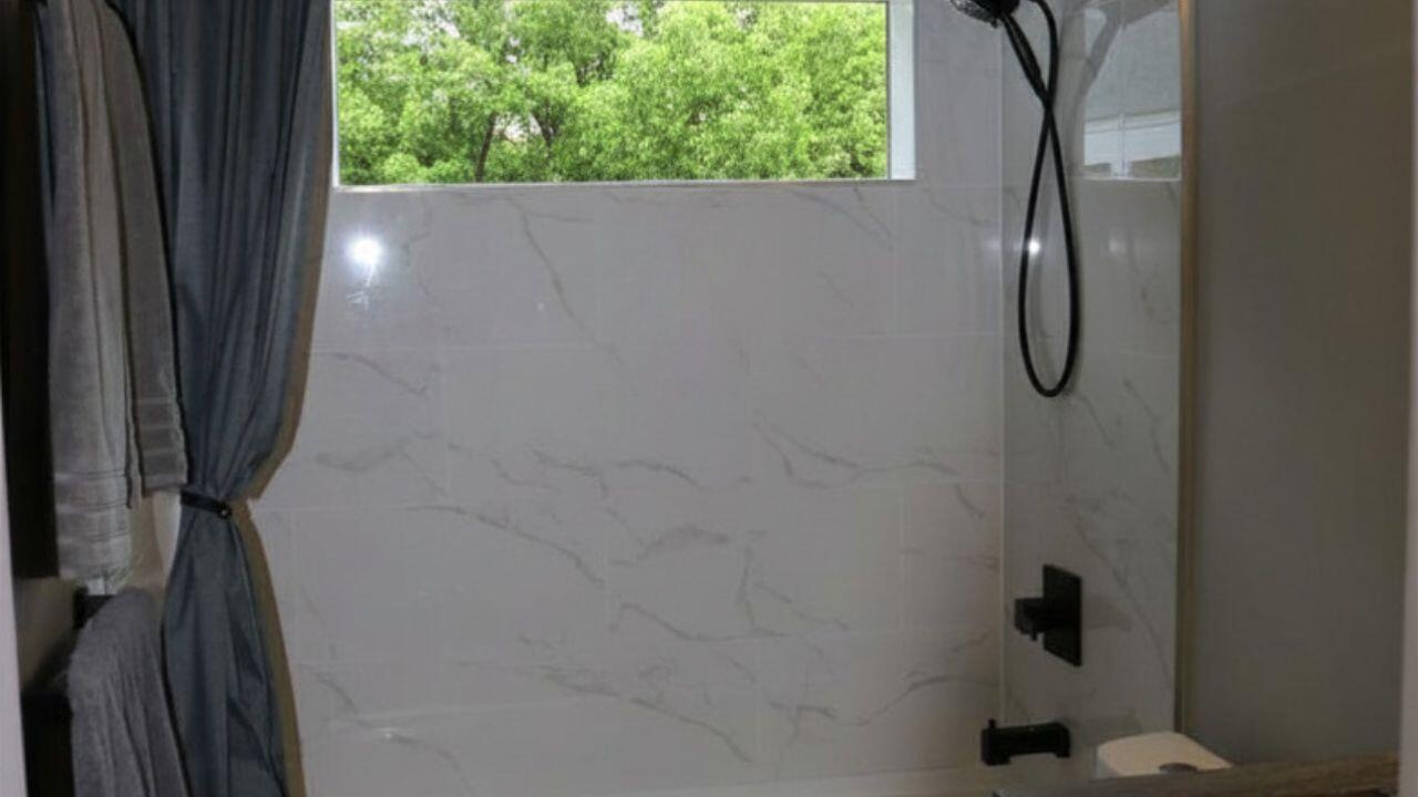 MAIN BATHROOM SHOWERUpdated main bathroom shower showcases modern finishes and a clean contemporary design. Wilton Manors home for sale, heated saltw
