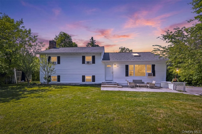 White siding residence featuring a prominent front lawn and a concrete patio