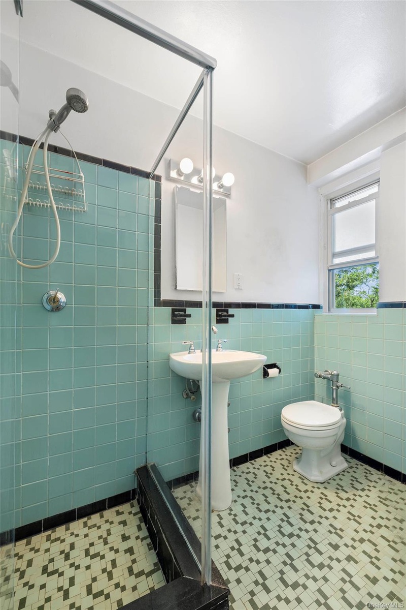 Bathroom featuring a glass-enclosed shower, pedestal sink, and patterned floor tiling