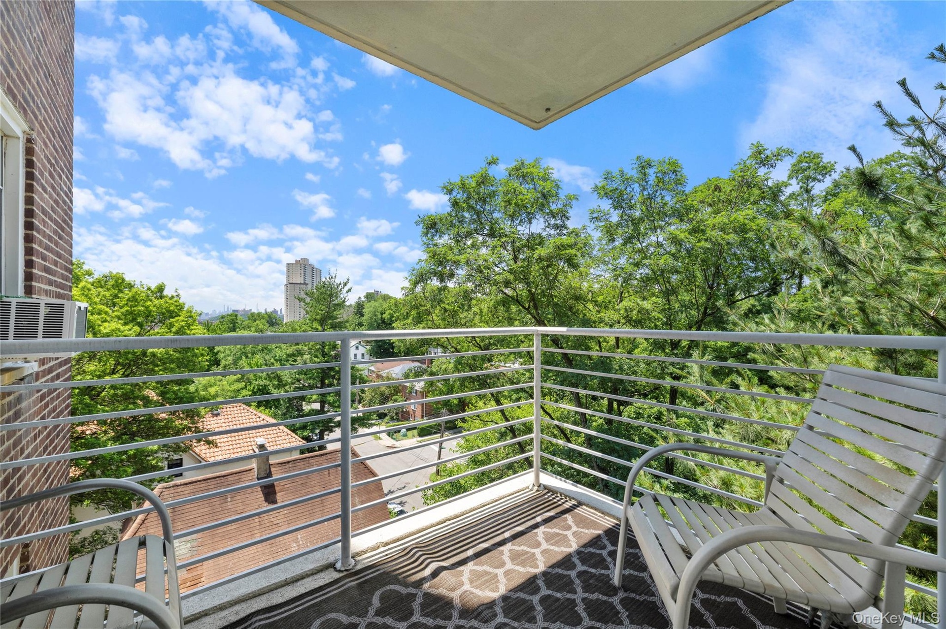 Balcony space featuring a patterned area rug, white metal railing, and a brick exterior wall