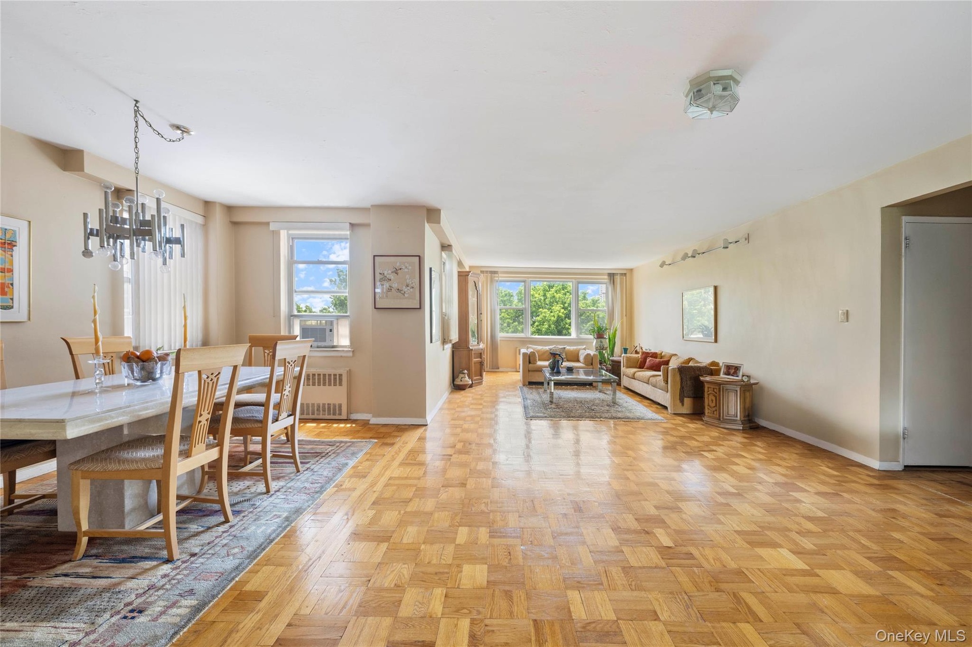 Spacious open-concept living and dining areas featuring parquet wood flooring throughout