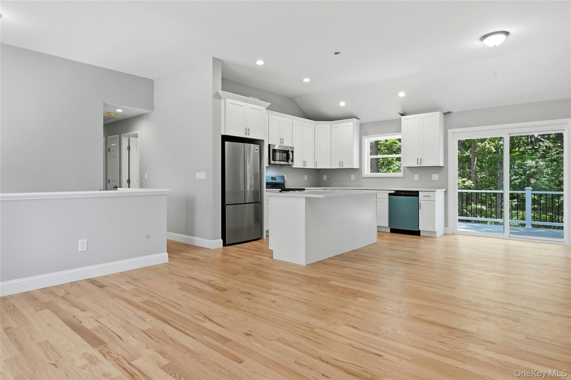The spacious kitchen features a large center island, quartz countertops, white soft-close cabinets, and a complete stainless steel appliance package .