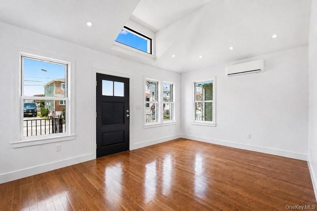 Entry area featuring a dark paneled door with glass inserts, wood-finish flooring, and white walls