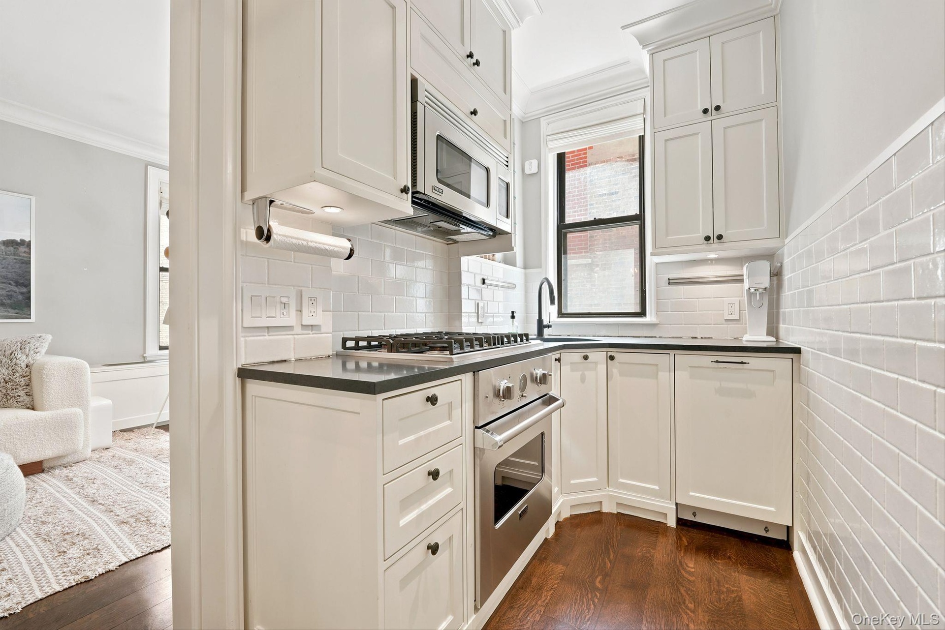 Kitchen featuring white shaker cabinetry, stainless steel appliances, dark countertops, and subway tile backsplash