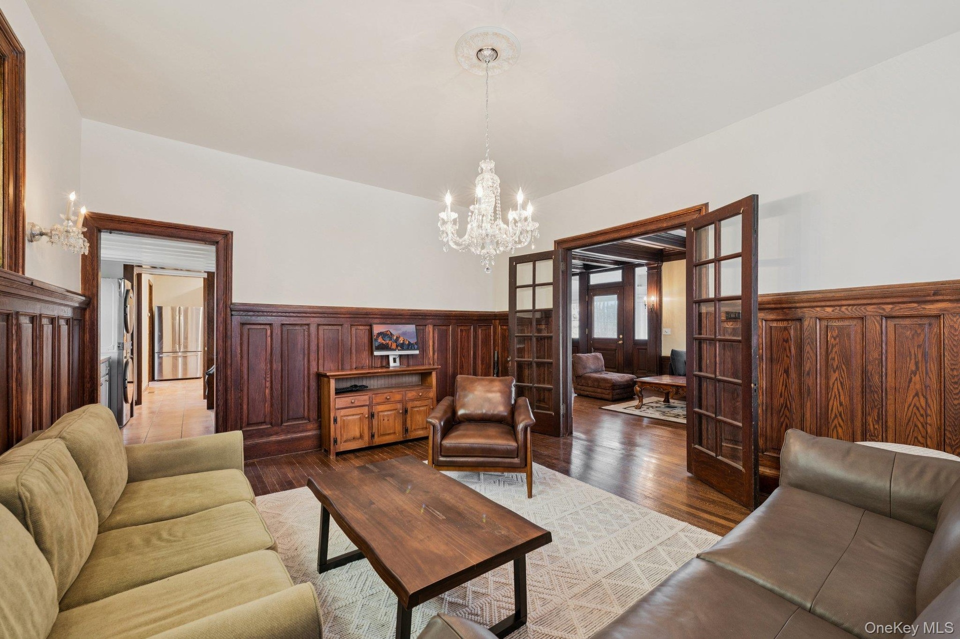 Living room with a wainscoted wall, a chandelier, french doors, and hardwood / wood-style floors