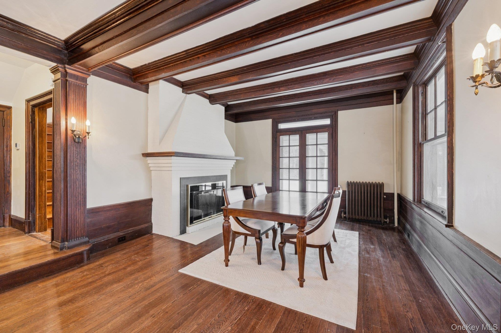 Dining area featuring radiator, dark wood finished floors, a fireplace, french doors, and ornamental molding