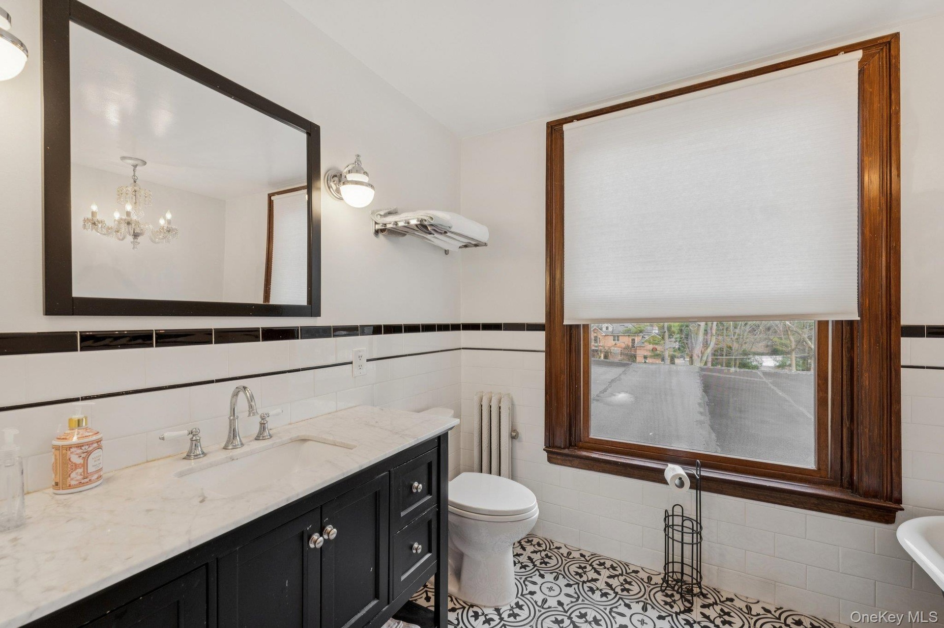 Bathroom with tile walls, radiator heating unit, vanity, a wainscoted wall, and light tile patterned floors
