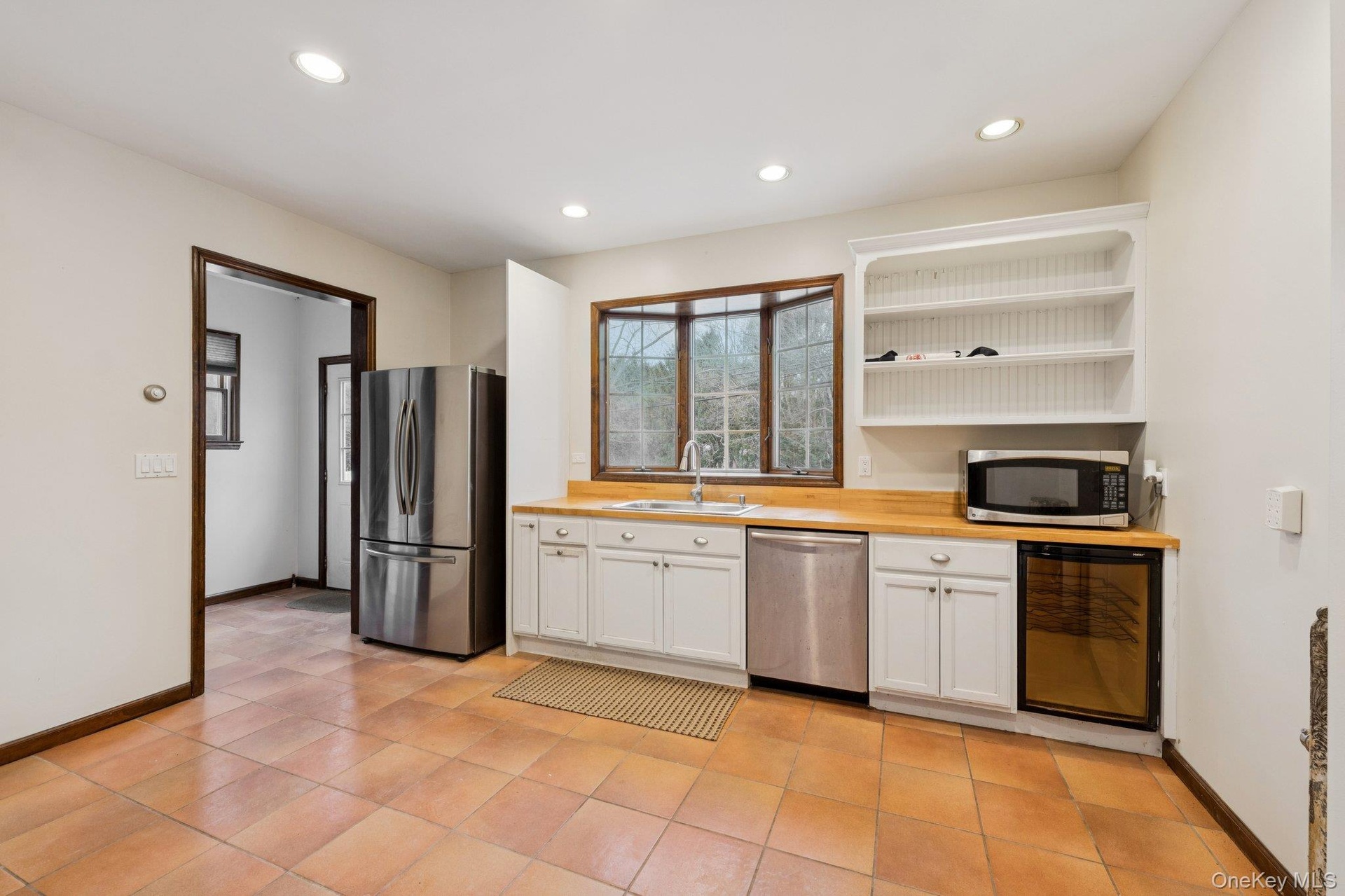 Kitchen with white cabinets, stainless steel appliances, open shelves, recessed lighting, and beverage cooler