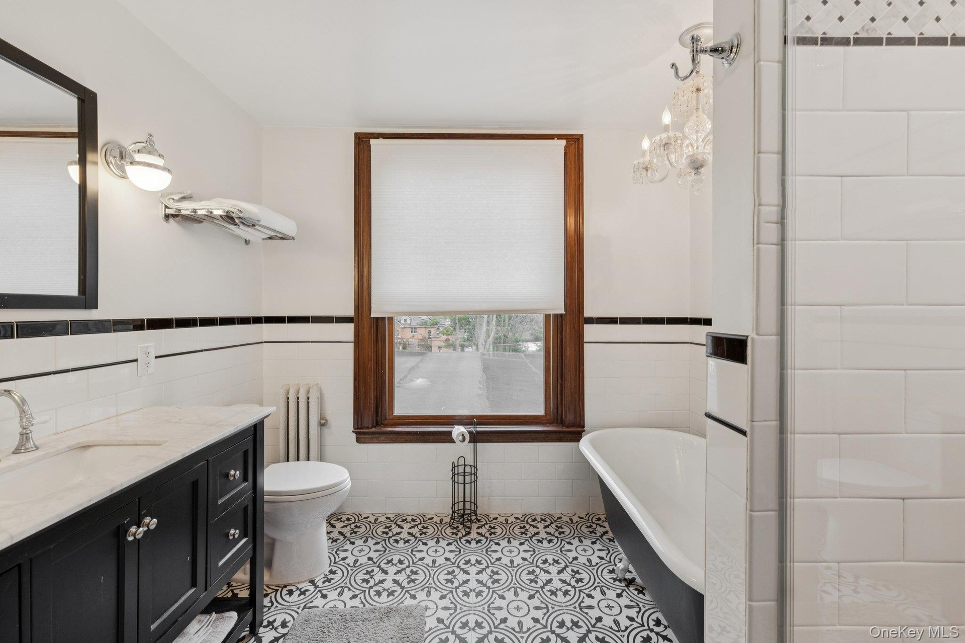Bathroom featuring tile walls, a wainscoted wall, a freestanding bath, radiator, and vanity