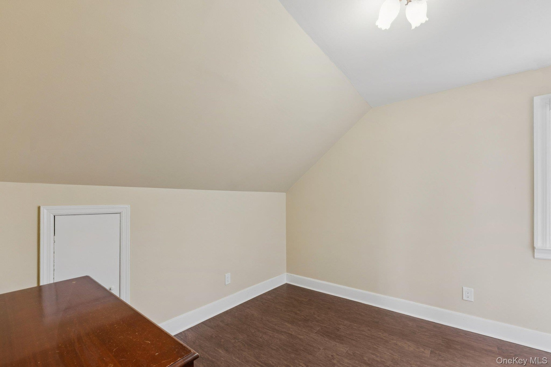Bonus room with lofted ceiling and dark wood finished floors