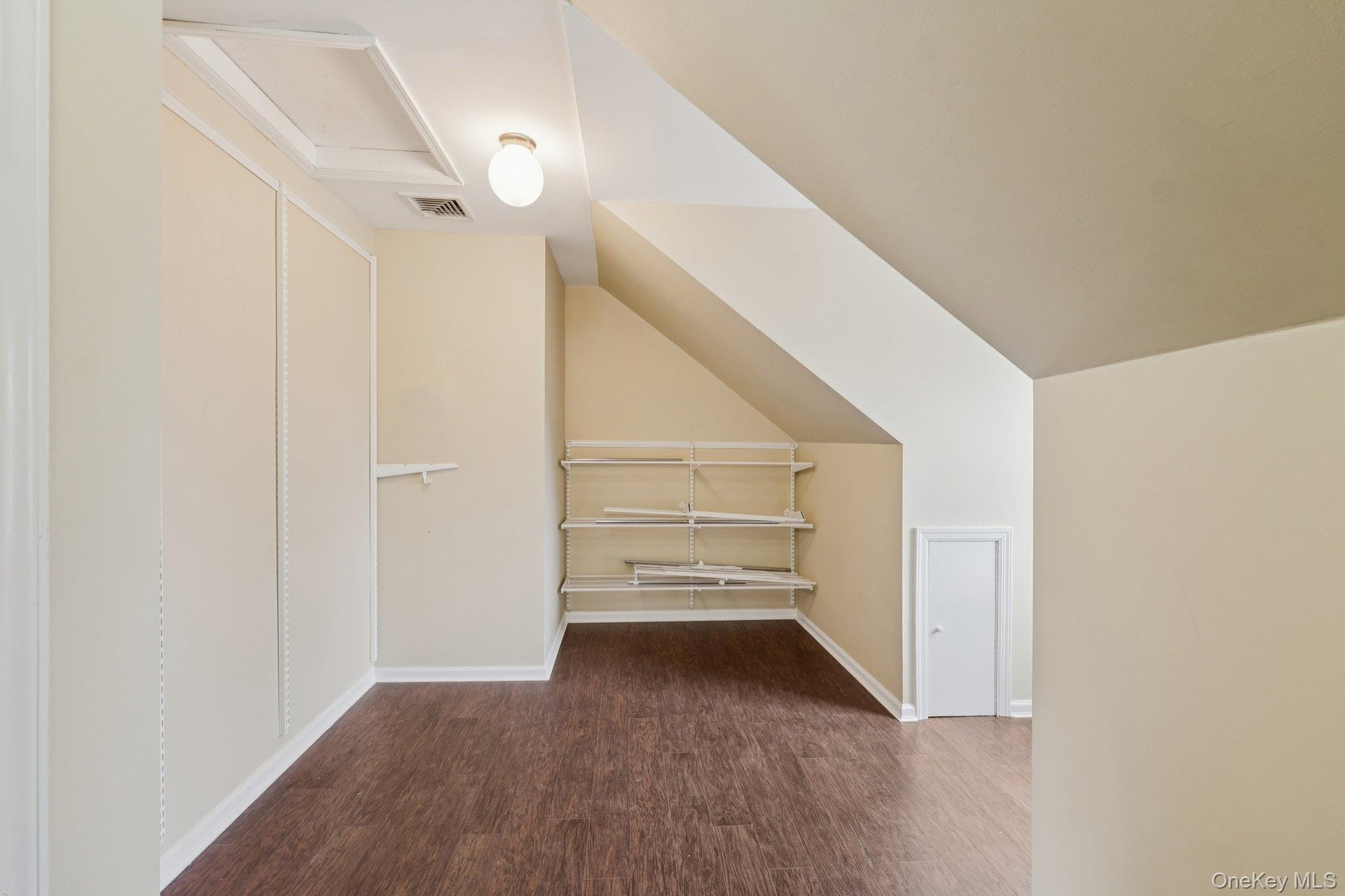 Bonus room featuring dark wood finished floors, lofted ceiling, and attic access