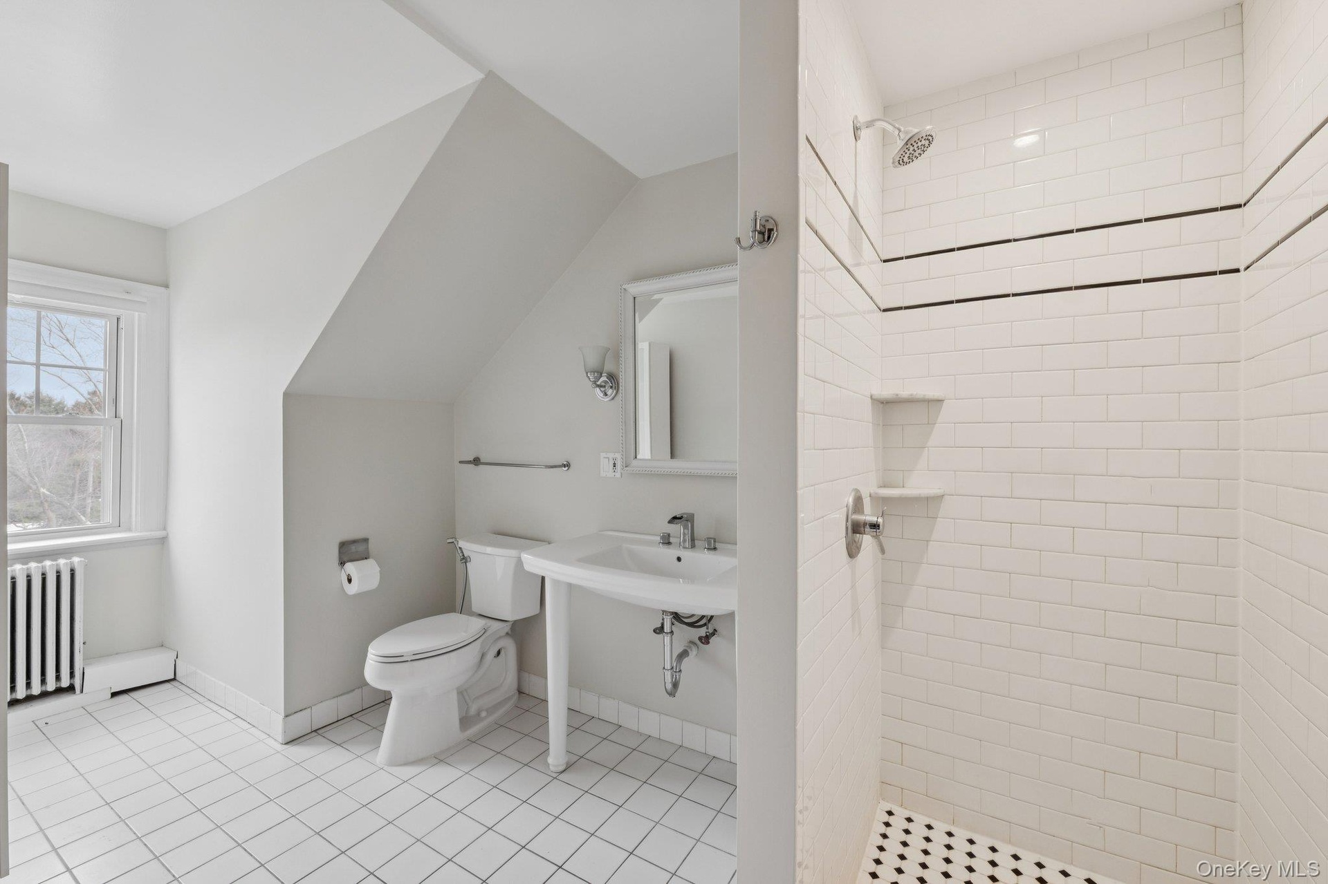 Bathroom featuring radiator, a stall shower, lofted ceiling, and light tile patterned floors