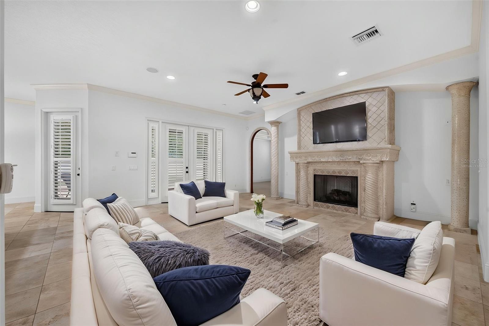 Virtually Staged. Family Room showcases a gas fireplace and French doors opening to the covered lanai and pool area
