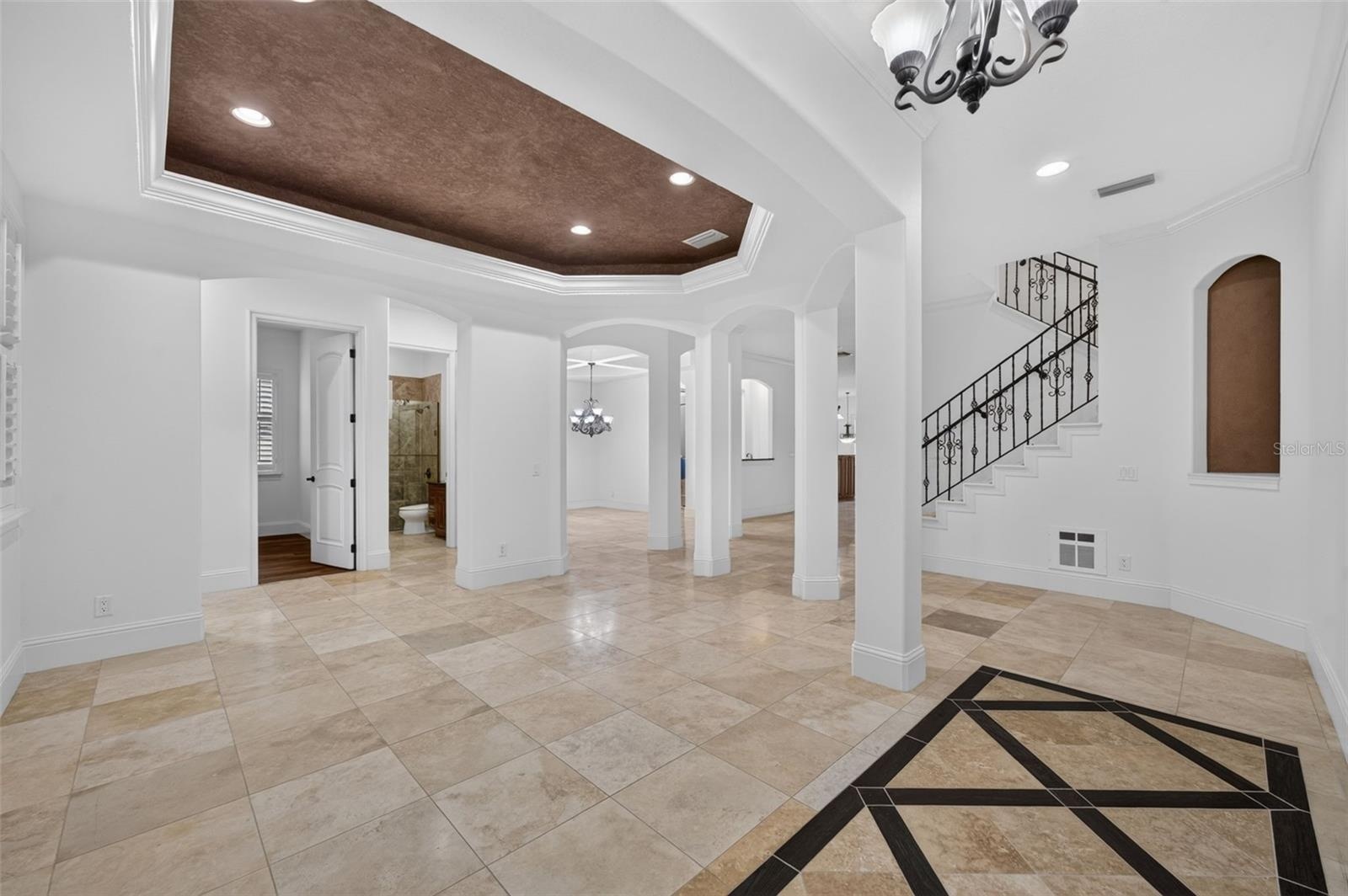 Living Room features a tray ceiling, travertine flooring & high ceilings