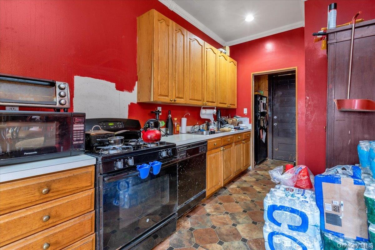 Kitchen with ornamental molding and black appliances
