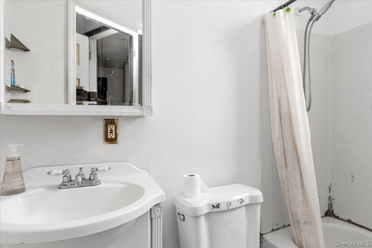 Full bathroom featuring shower / bath combination with curtain, sink, and toilet