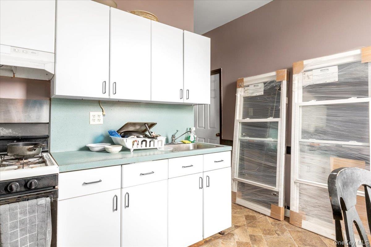 Kitchen featuring white cabinets, sink, and range with gas cooktop