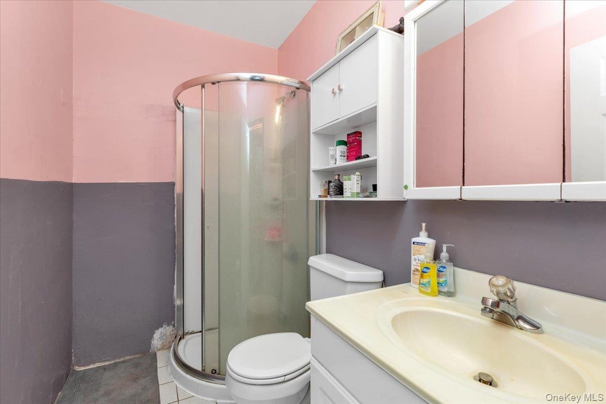 Bathroom featuring vanity, an enclosed shower, toilet, and tile patterned flooring